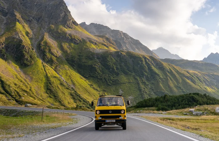 A yellow VW bus driving through the mountains