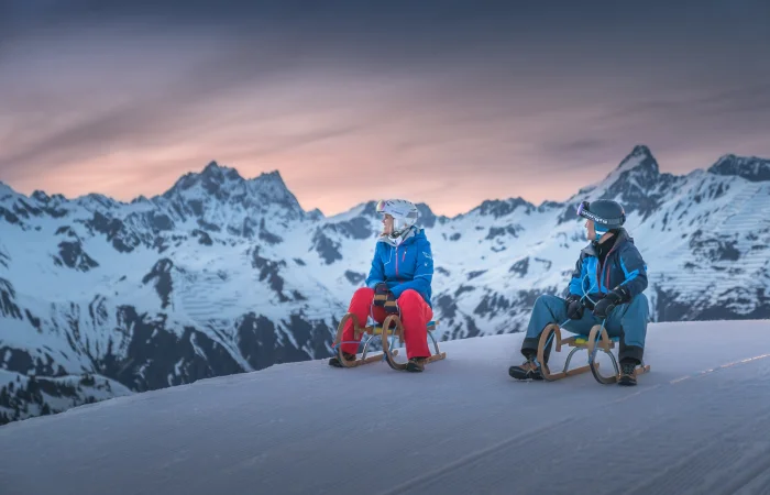Personen auf Rodeln mit Blick auf die Berge