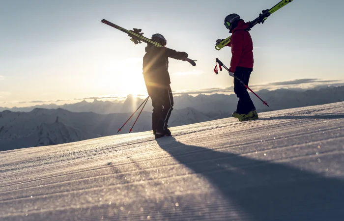 Two skiers on the slope watching the sunset