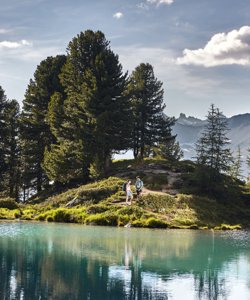 Wanderer machen Pause am Berglisee mit Blick auf die Alpen
